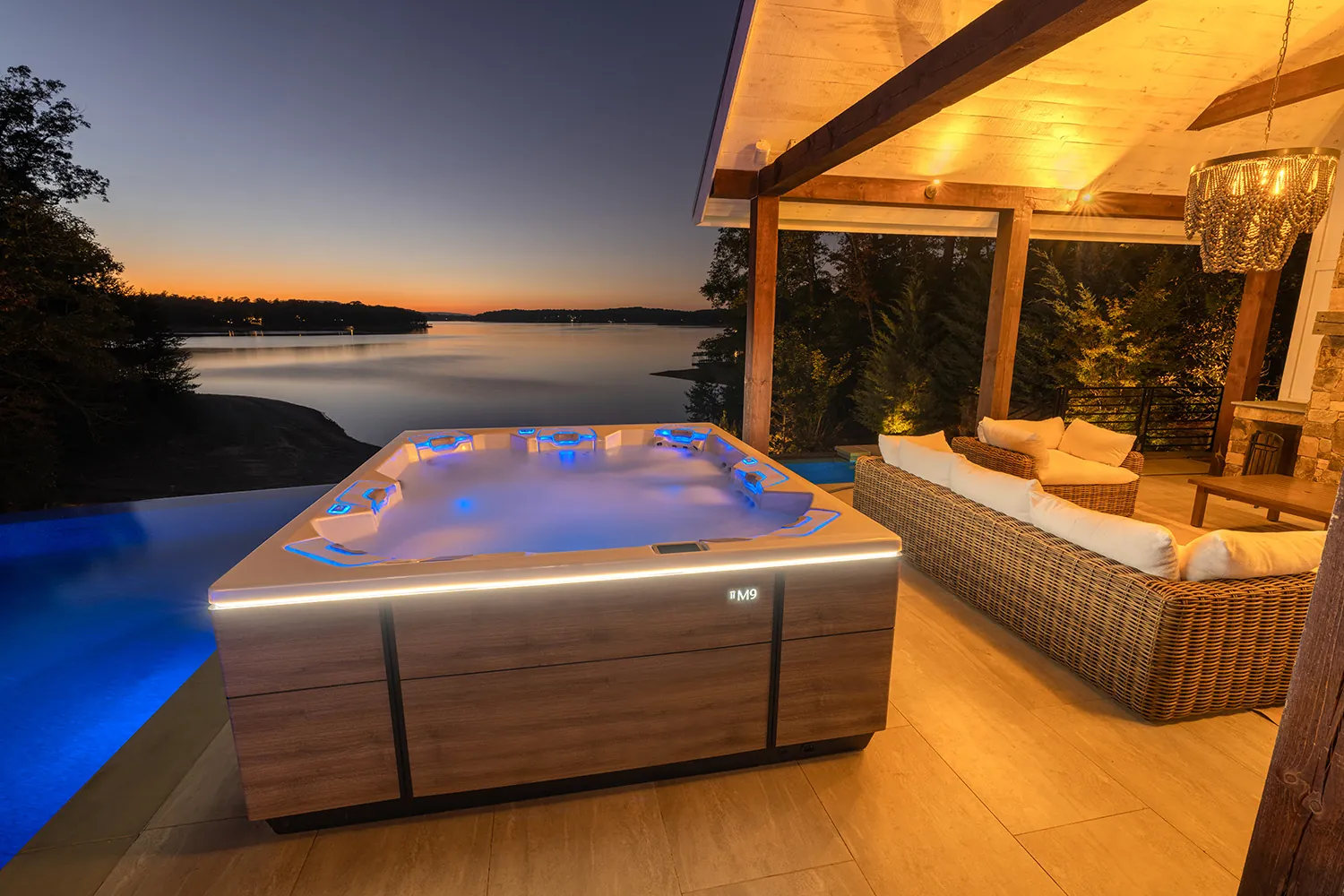 Bullfrog M9 spa glowing beside an infinity pool at dusk