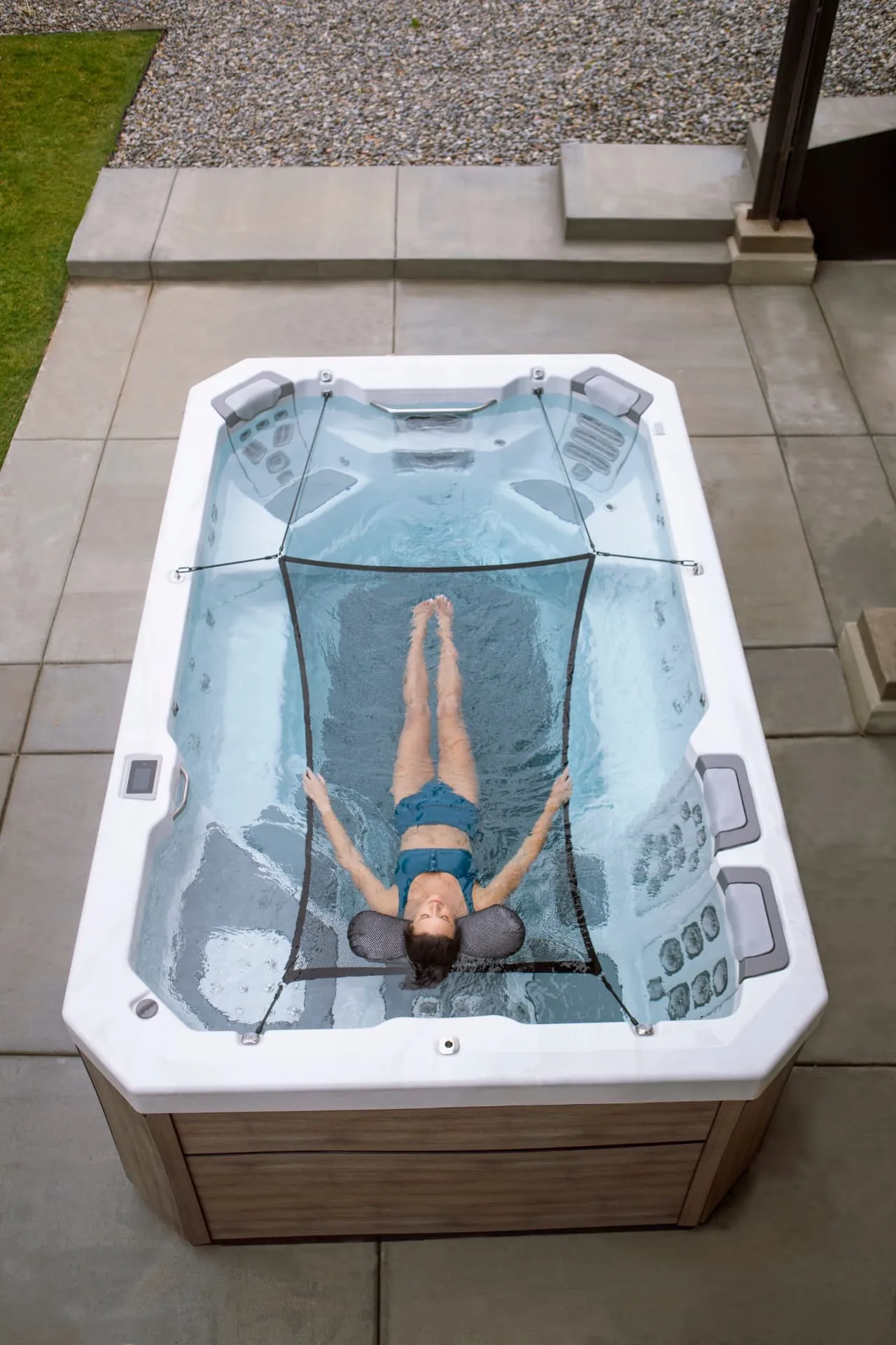 Woman floating in a Bullfrog Swim Series spa with timber siding