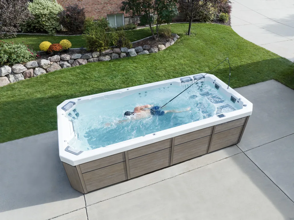Swimmer using the current in a Bullfrog Swim Series spa on a backyard patio